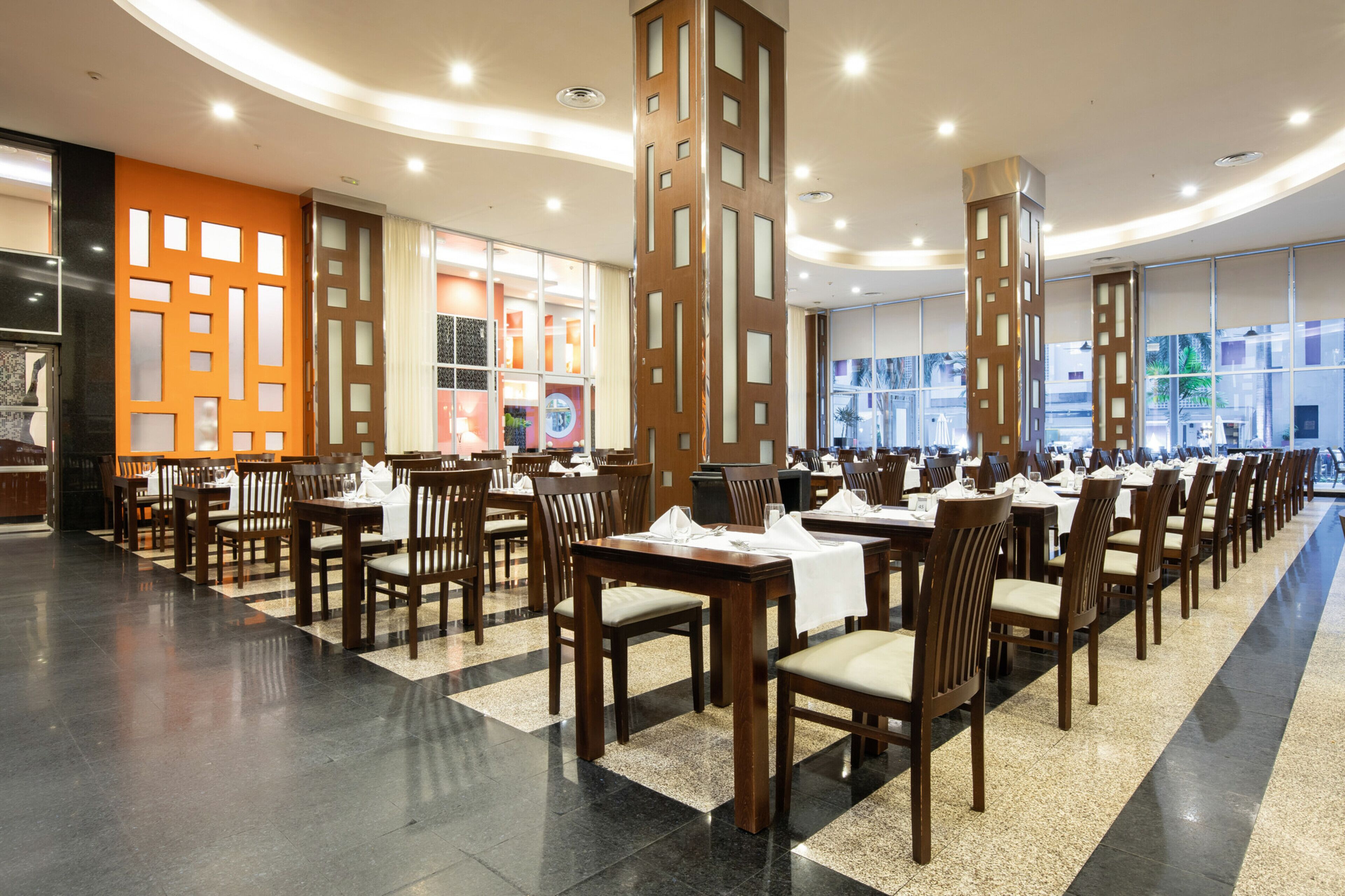 Een ruime restaurantruimte met meerdere eettafels en stoelen, een modern interieur en grote ramen met uitzicht.