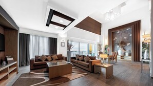 A modern living room with a sofa set, a coffee table, and a dining area with chairs and a table.