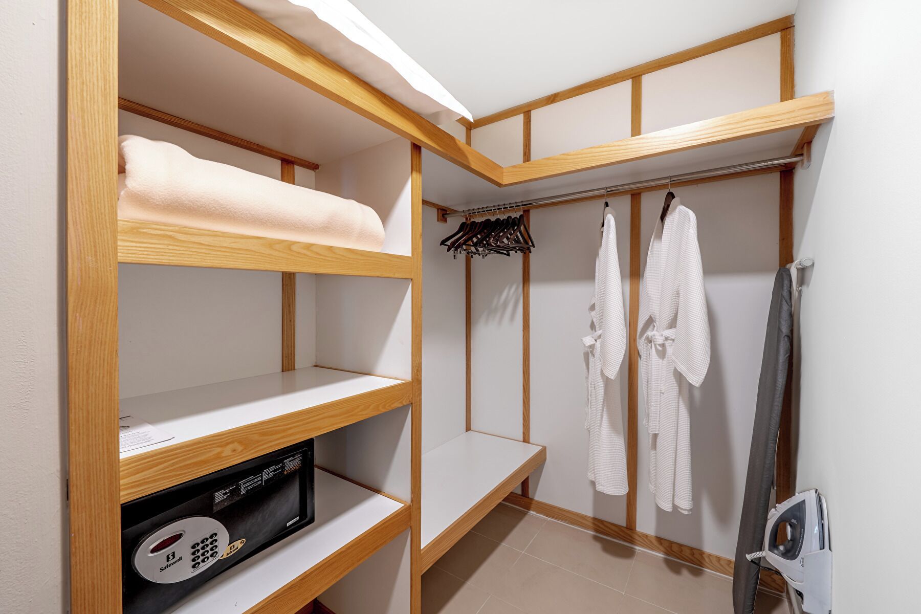 A compact room with wooden shelves, a drying rack, and a built-in ironing station.