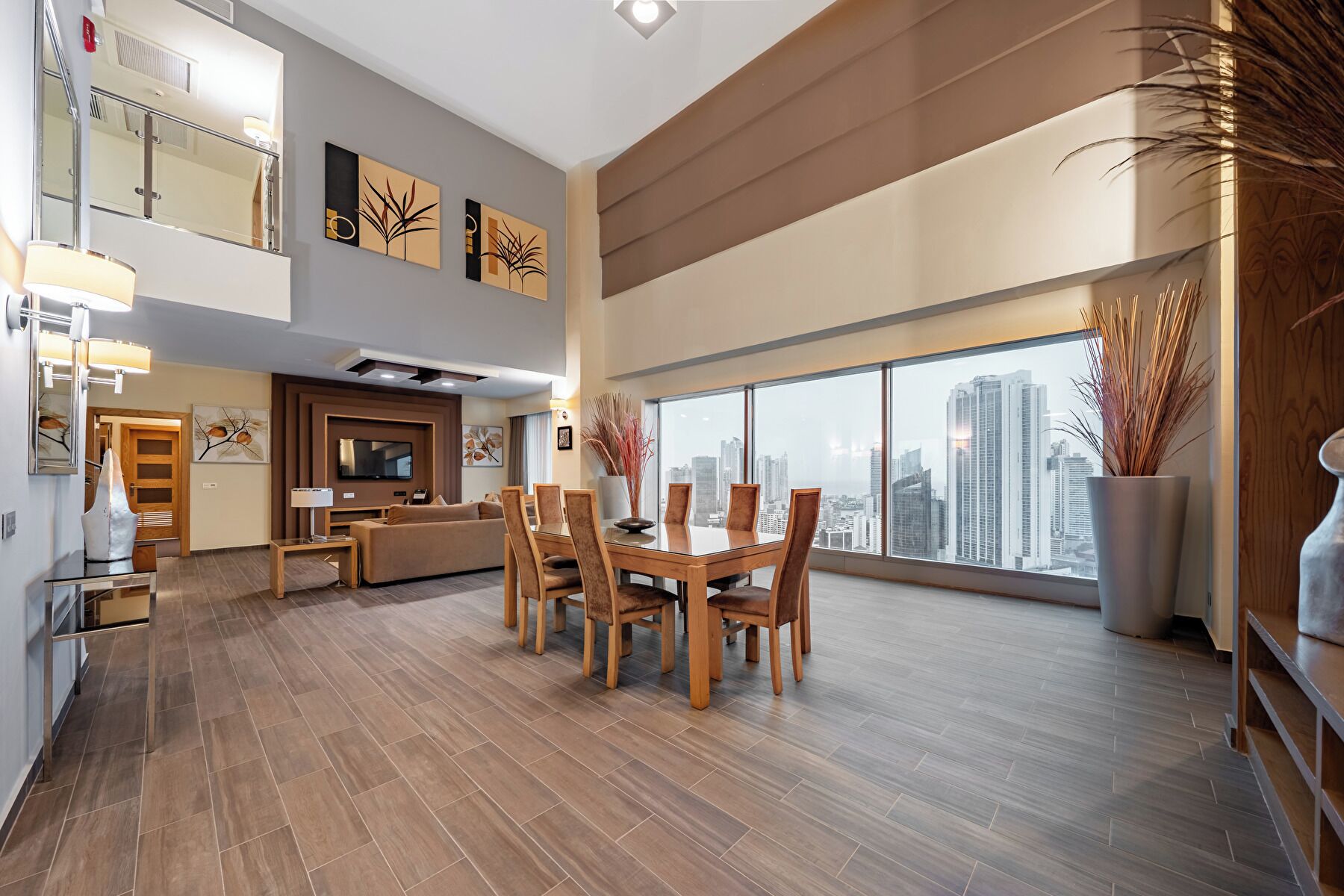 A spacious living area with a dining table, sofas, and a TV.