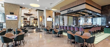 A modern bar area with a counter, seating, and a television screen.