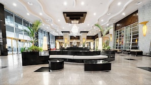 A spacious lobby with a central seating area, a chandelier, and a modern ceiling design.