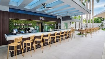 A bar area with a counter, bar stools, and a ceiling fan.