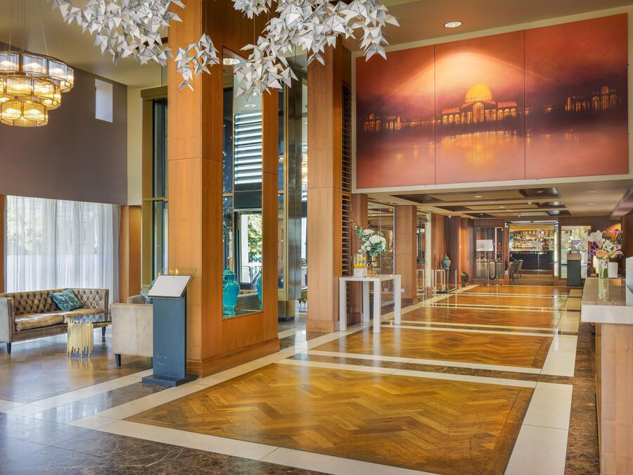 A hotel lobby with a reception desk, seating area, and a large window.