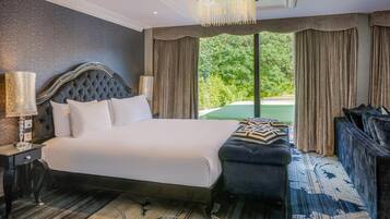 A large bed with a tufted headboard, a bedside lamp, and a bench with a patterned cushion.