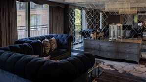 A modern living room with a dark blue sofa, a wooden cabinet, and a patterned rug. - Hilton London Syon Park (Brentford)