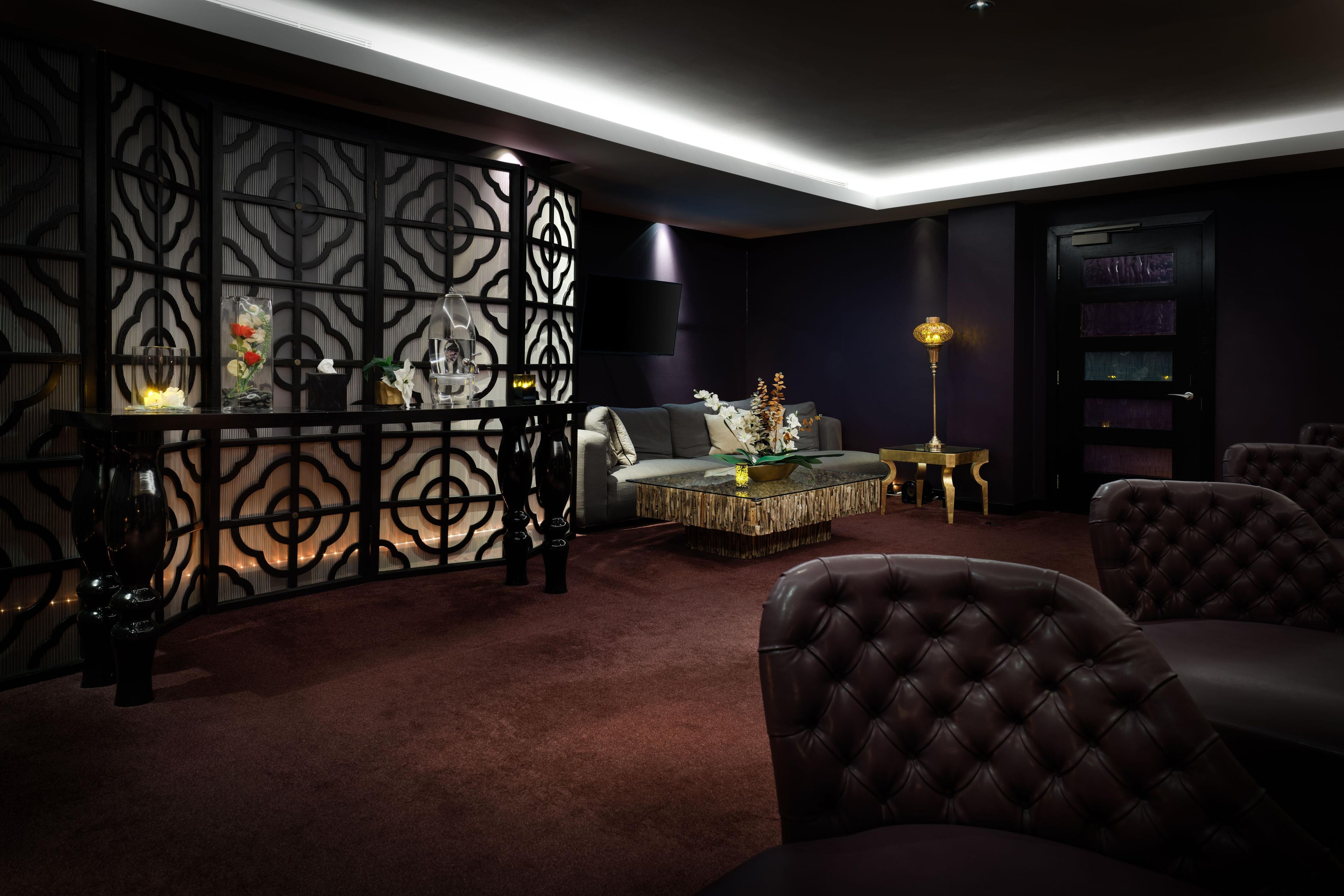 A modern living room with a dark color scheme, a sectional sofa, a coffee table, and decorative items.