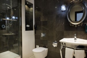 Un baño moderno con ducha envuelta en cristal, inodoro blanco, tocador con espejo y barra para toallas.