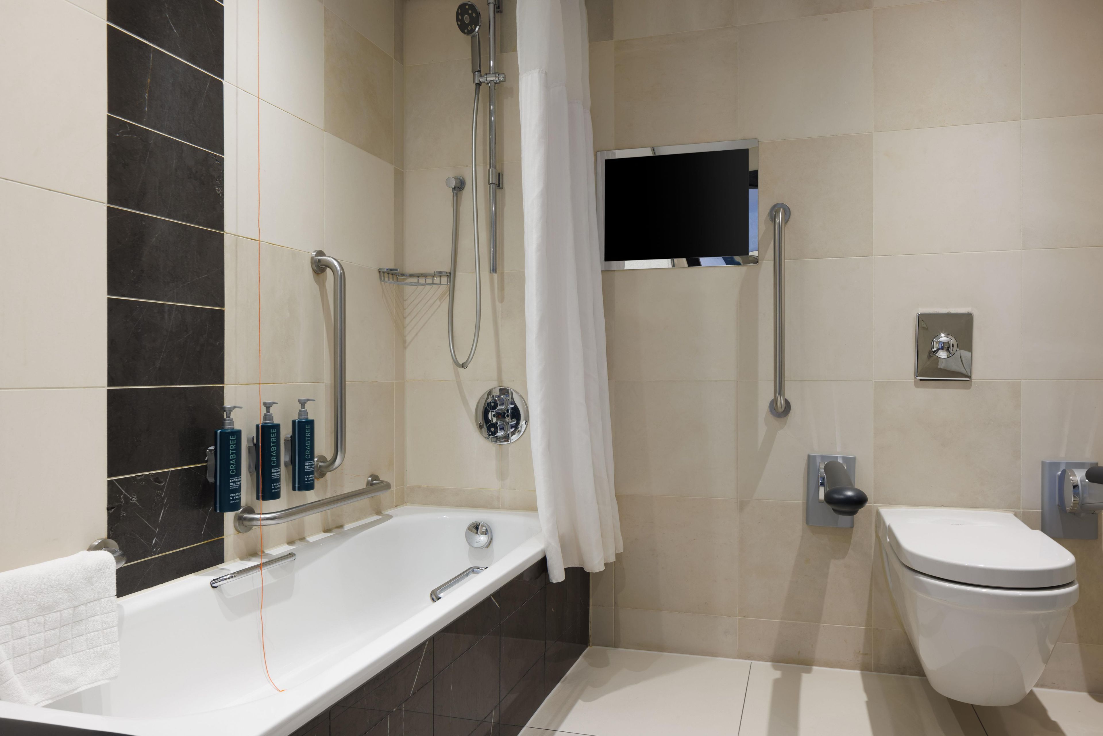 A modern bathroom with a bathtub, toilet, and shower.