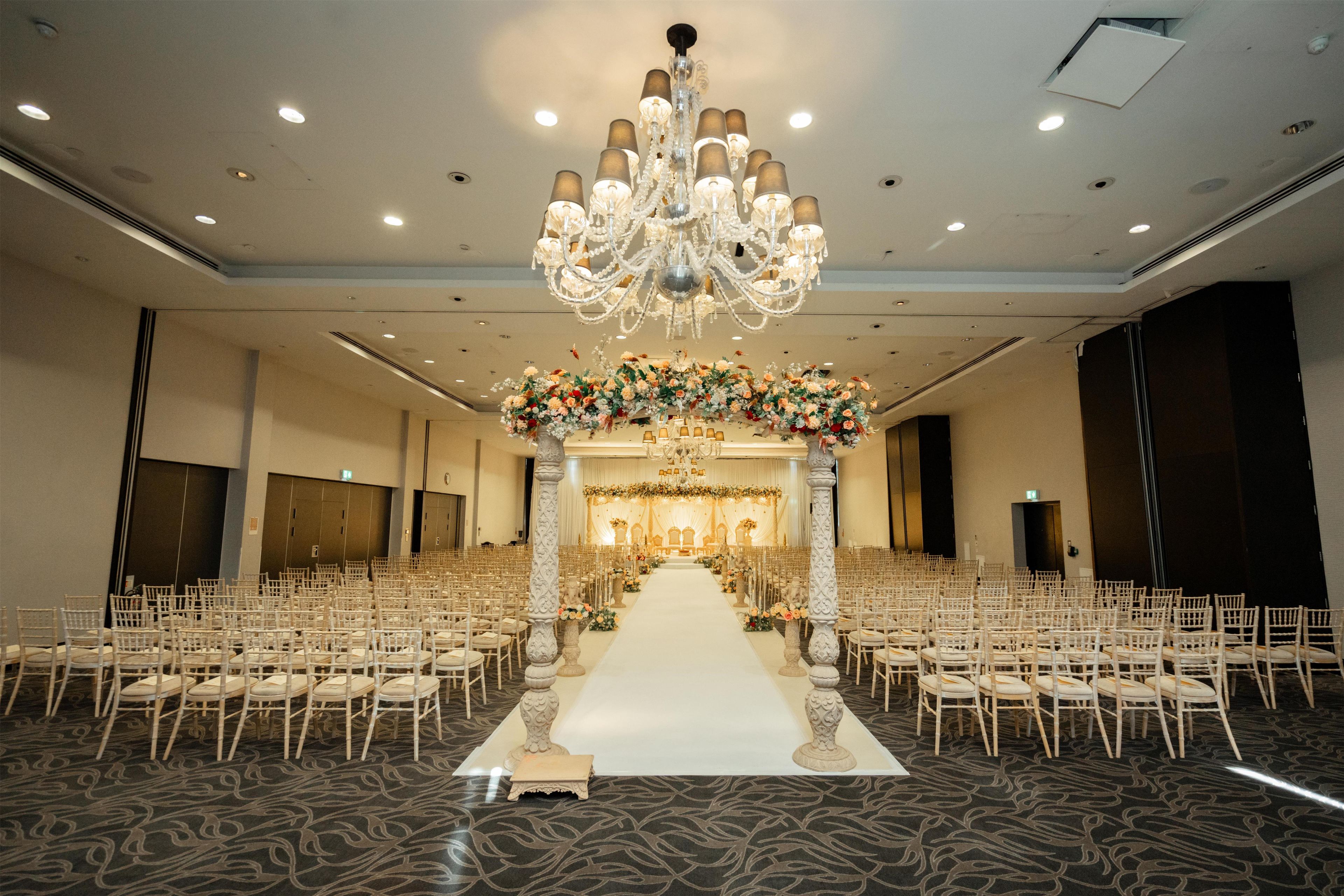 A large hall with rows of chairs, a central aisle, and a decorative floral arrangement at the front.