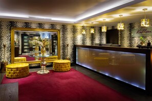 A hotel lobby with a large mirror, a reception desk, and a red carpet.