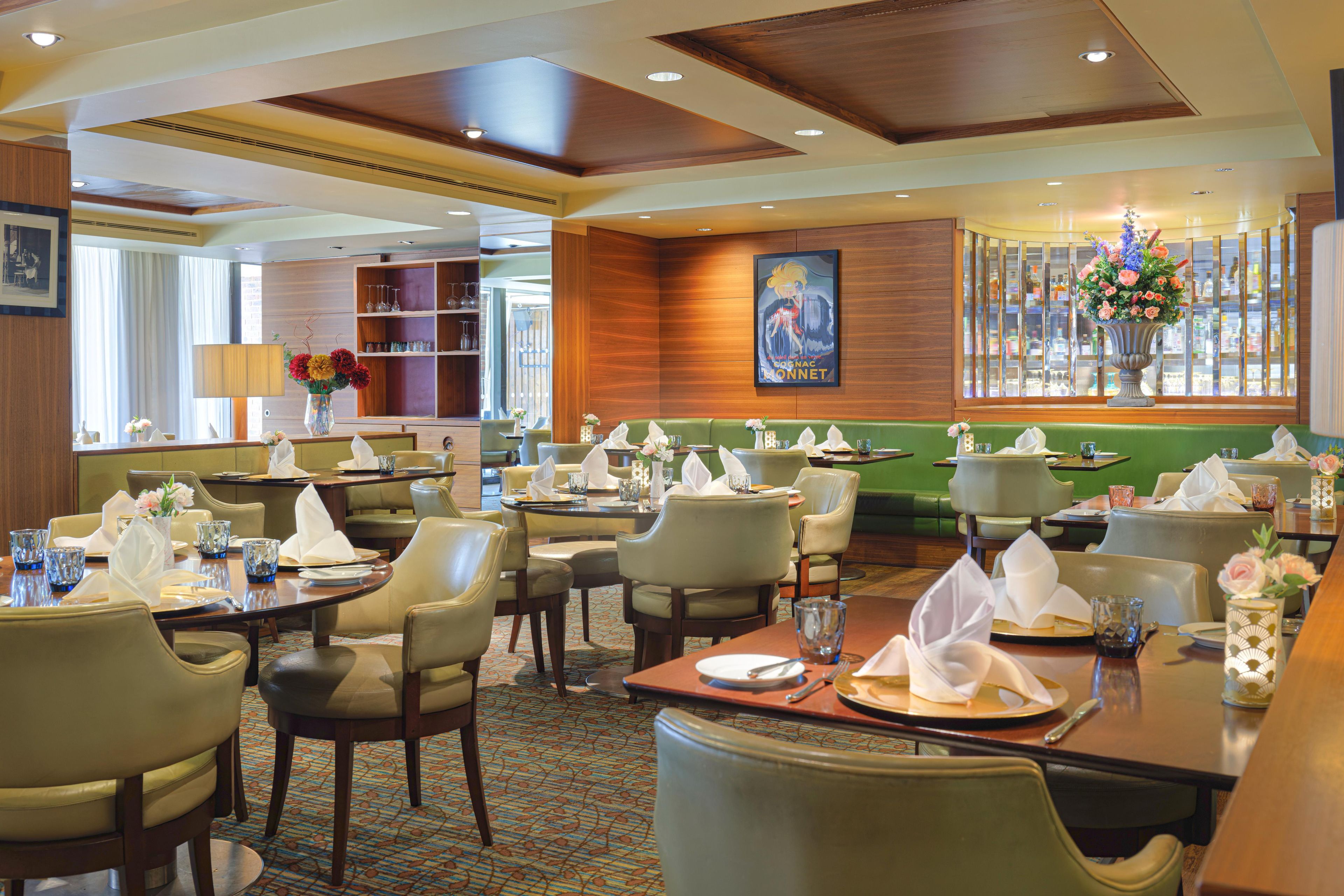 A restaurant with multiple dining tables, chairs, and a variety of table settings.