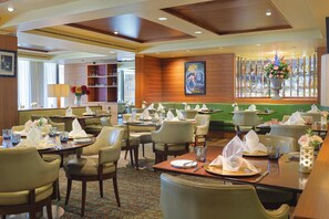A restaurant with multiple dining tables, chairs, and a variety of table settings. - Hilton London Syon Park (Brentford)