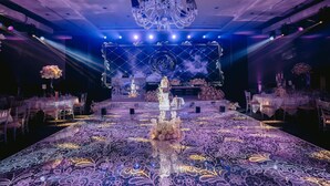 A banquet hall with a central stage, chandeliers, and tables set for an event. - Hilton London Syon Park (Brentford)