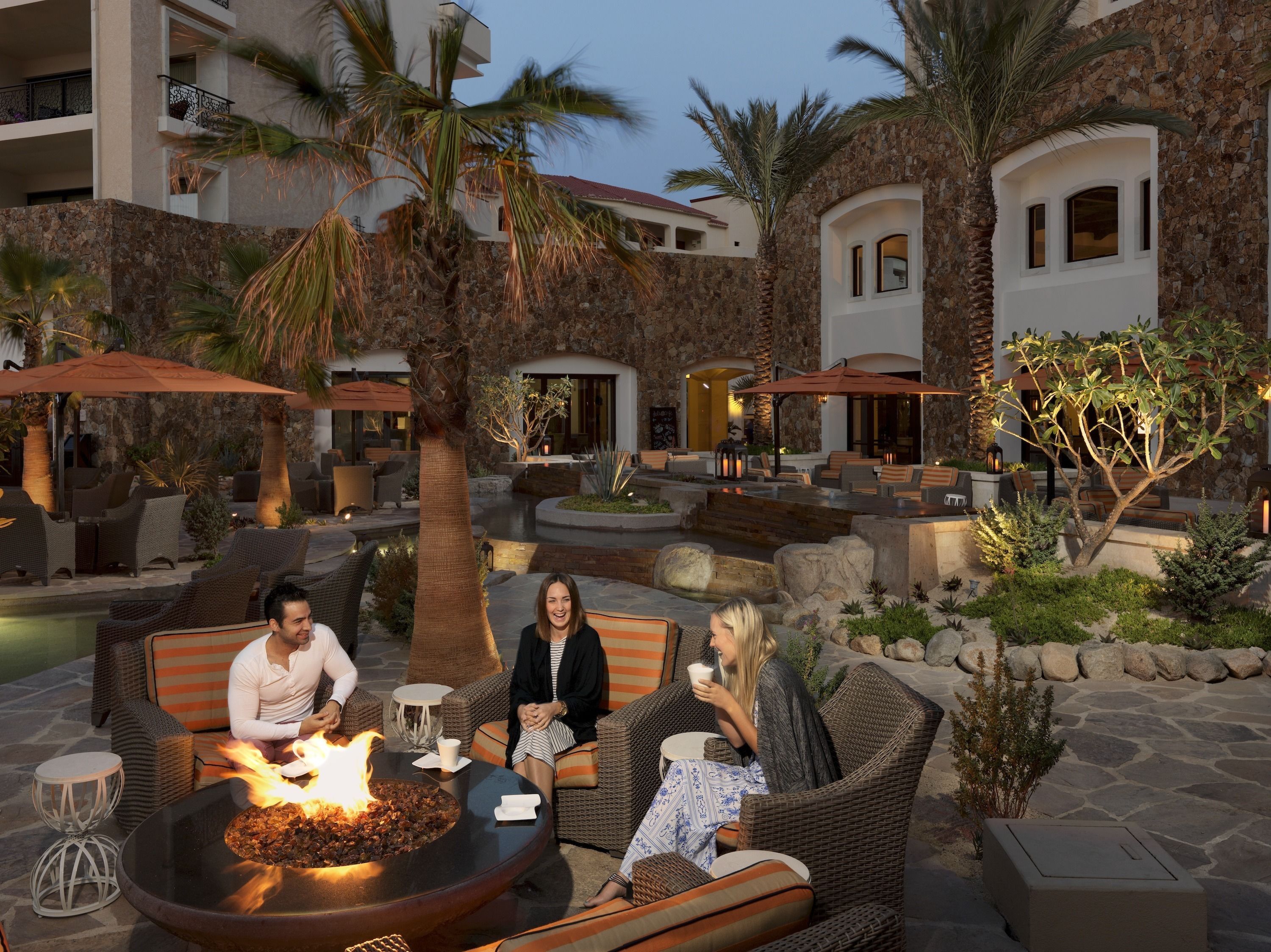 An outdoor seating area with wicker furniture, a fire pit, and a pool.