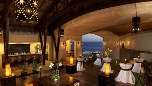 Un ambiente interior lujoso con una zona de bar, disposición de asientos y vistas al océano.