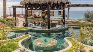 Un resort con zona de piscina, bar y una estructura de techo de paja.