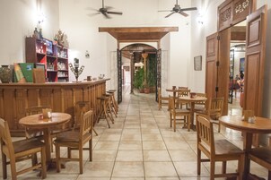 Un restaurante con mobiliario de madera, una zona de bar y plantas en macetas.