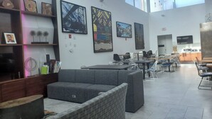 Een modern interieur met een grijze bank, een eethoek met stoelen en kunstwerken aan de muren.