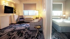Een hotelkamer met een bank, fauteuil, nachtkastje en een bed.
