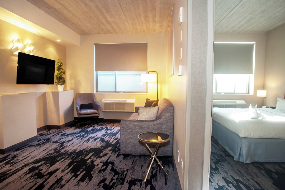 Een hotelkamer met een bank, fauteuil, nachtkastje en een bed.
