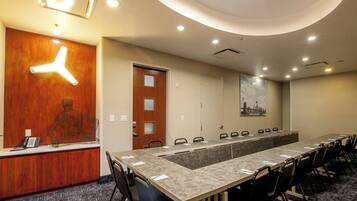 A conference room with a long table, chairs, a reception desk, and a wooden wall with a light fixture.