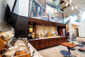 Un café moderno con mostrador de servicio de alimentos, zona de estar y un mural de una calle urbana.