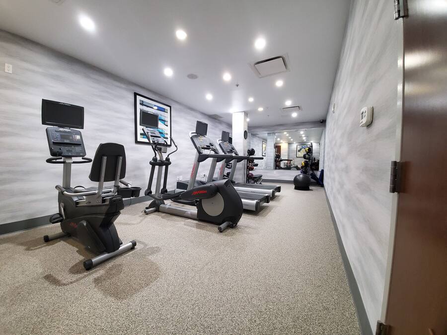 Et fitnesscenter med løbebånd, crosstrainere og træningsudstyr.