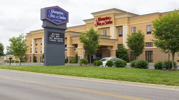 A Hampton Inn & Suites by Hilton with a signboard advertising free WiFi, breakfast, hot buffet, and fitness center.