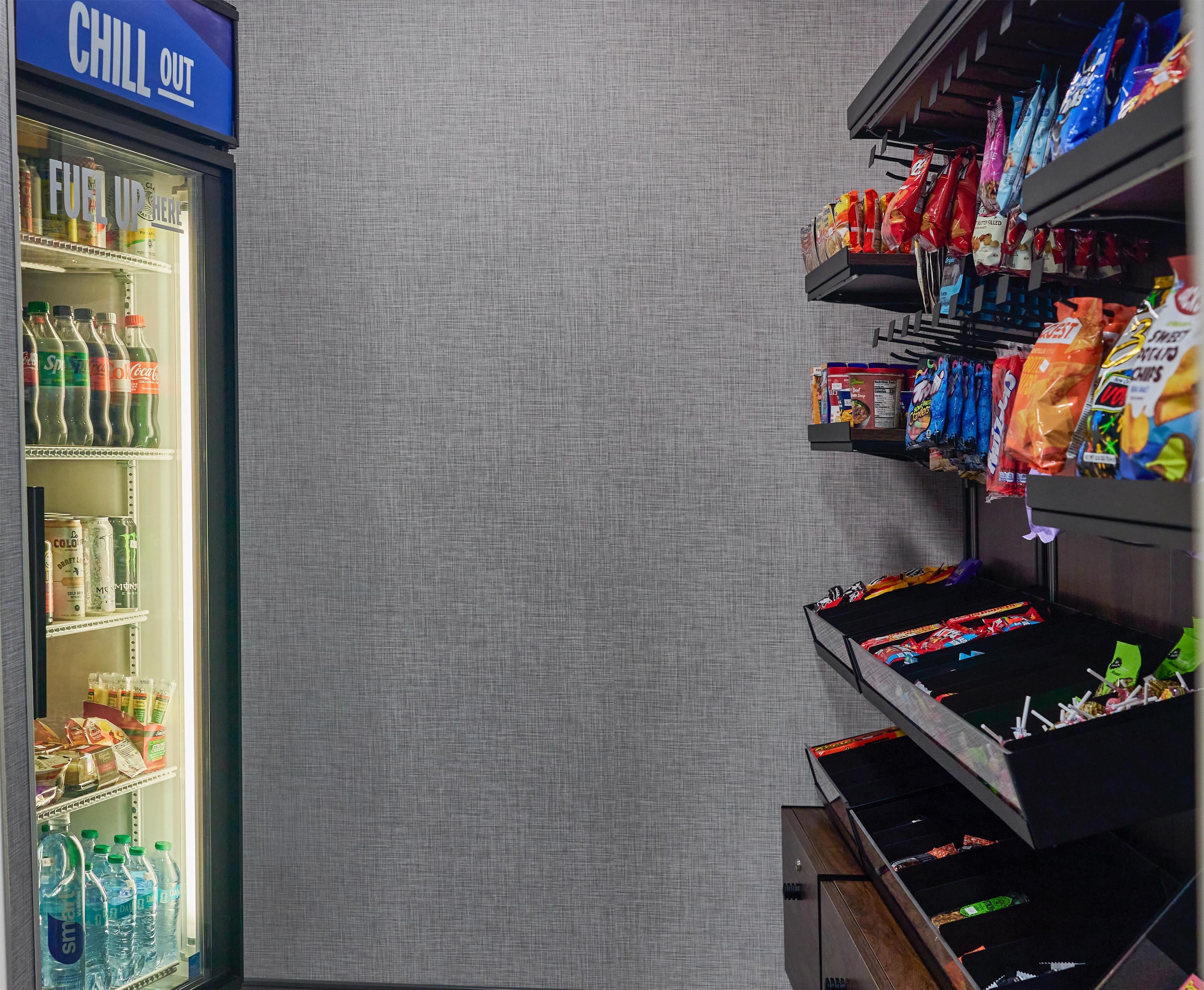 Una máquina expendedora llena de aperitivos y un refrigerador con bebidas.
