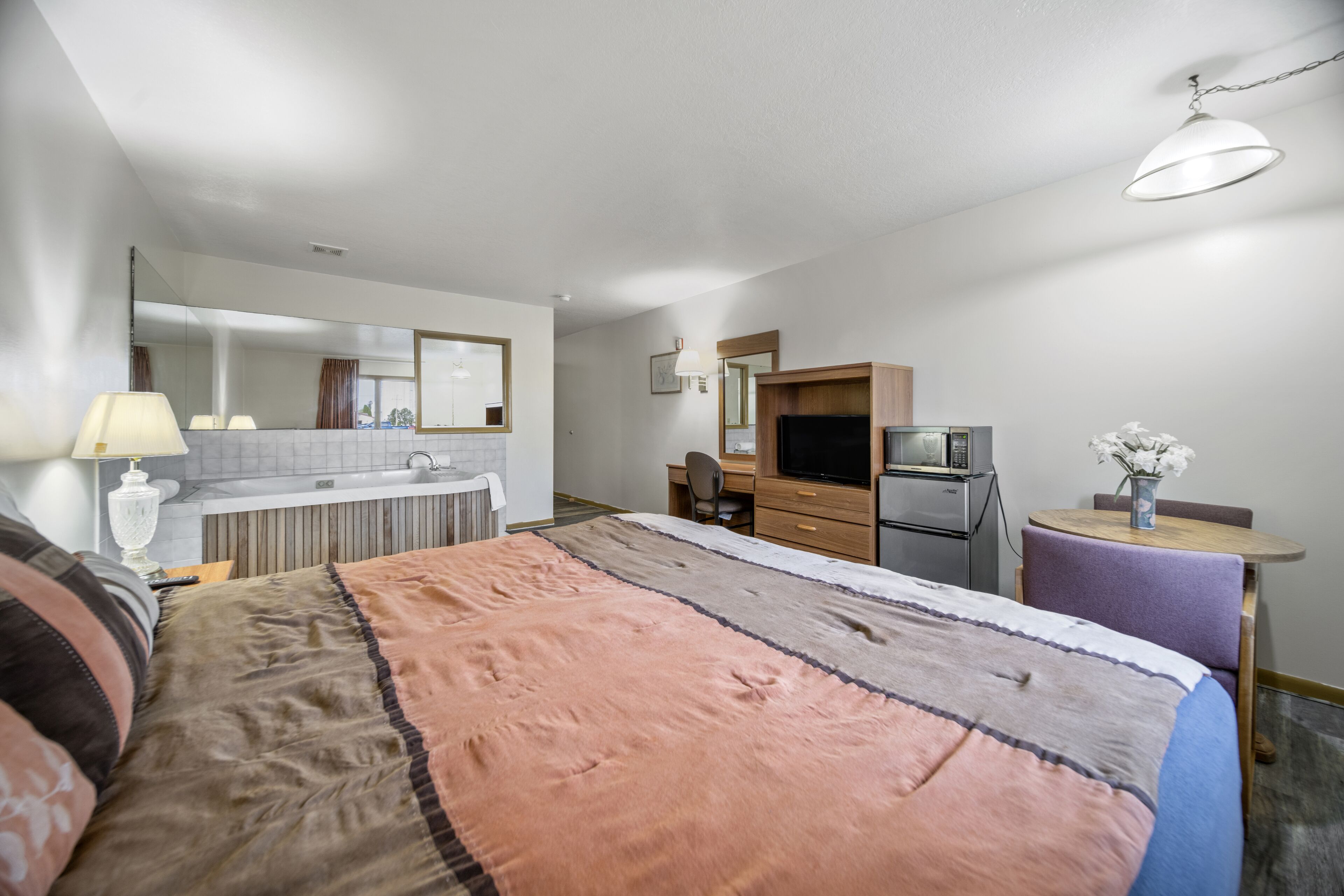 Habitación de hotel con una cama grande, un escritorio, kitchenette y baño.