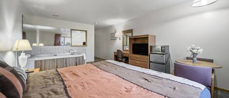 Habitación de hotel con una cama grande, un escritorio, kitchenette y baño.