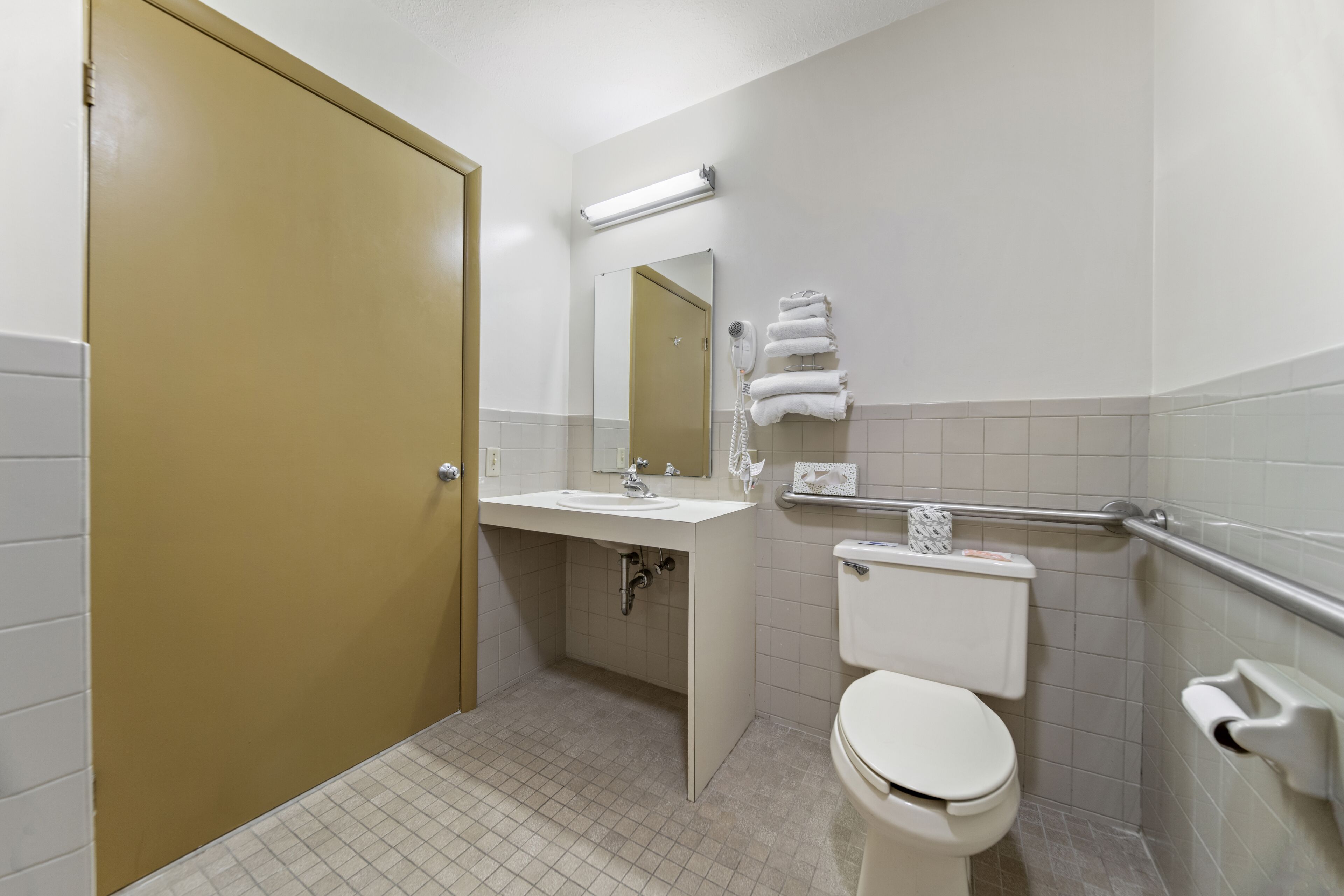 Baño con inodoro, lavabo, espejo y toallero.