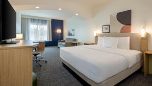 Una habitación de hotel con cama, escritorio, silla y televisor.