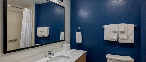 Un baño con un lavamanos blanco, un espejo, un inodoro y toallas colgadas en la pared.
