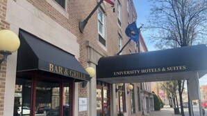 Un edificio con un letrero que dice 'BAR & GRILLE' y 'UNIVERSITY HOTELS & SUITES'.