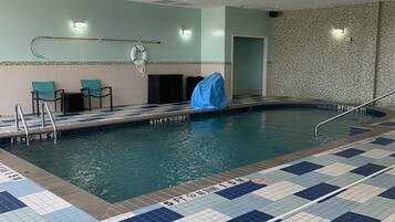 Una piscina interior con suelo de baldosas, un flotador salvavidas y un objeto cubierto en el borde de la piscina.