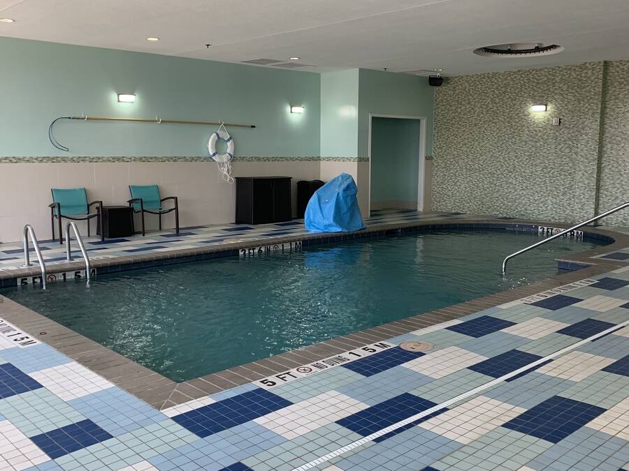 Una piscina interior con suelo de baldosas, un flotador salvavidas y un objeto cubierto en el borde de la piscina.