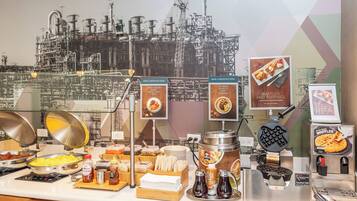 Uma área de buffet com diversas opções de café da manhã, incluindo waffles, iogurte e frutas.