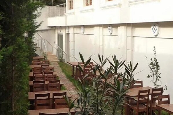 A building with a staircase leading to an upper level, surrounded by greenery and outdoor seating areas with tables and chairs. - Florya Konagi Hotel (ISTANBUL)