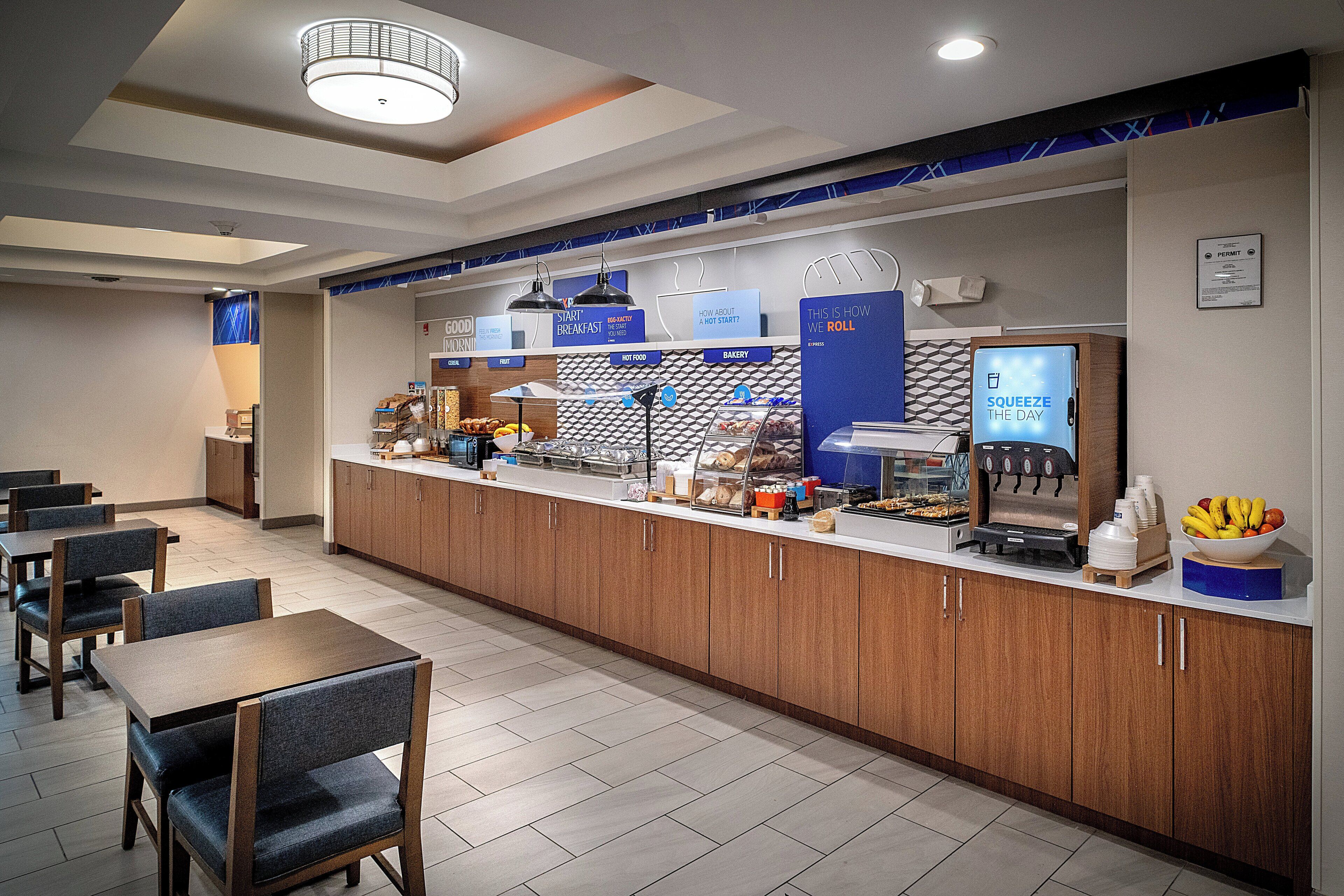 A modern breakfast bar with a coffee machine, a fruit bowl, and a sign that reads "SQUEEZE THE DAY".