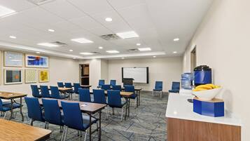 A conference room with tables and chairs, a whiteboard, and a water dispenser.