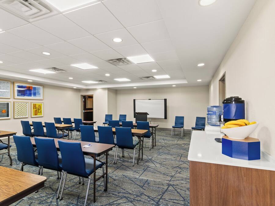 A conference room with tables and chairs, a whiteboard, and a water dispenser.