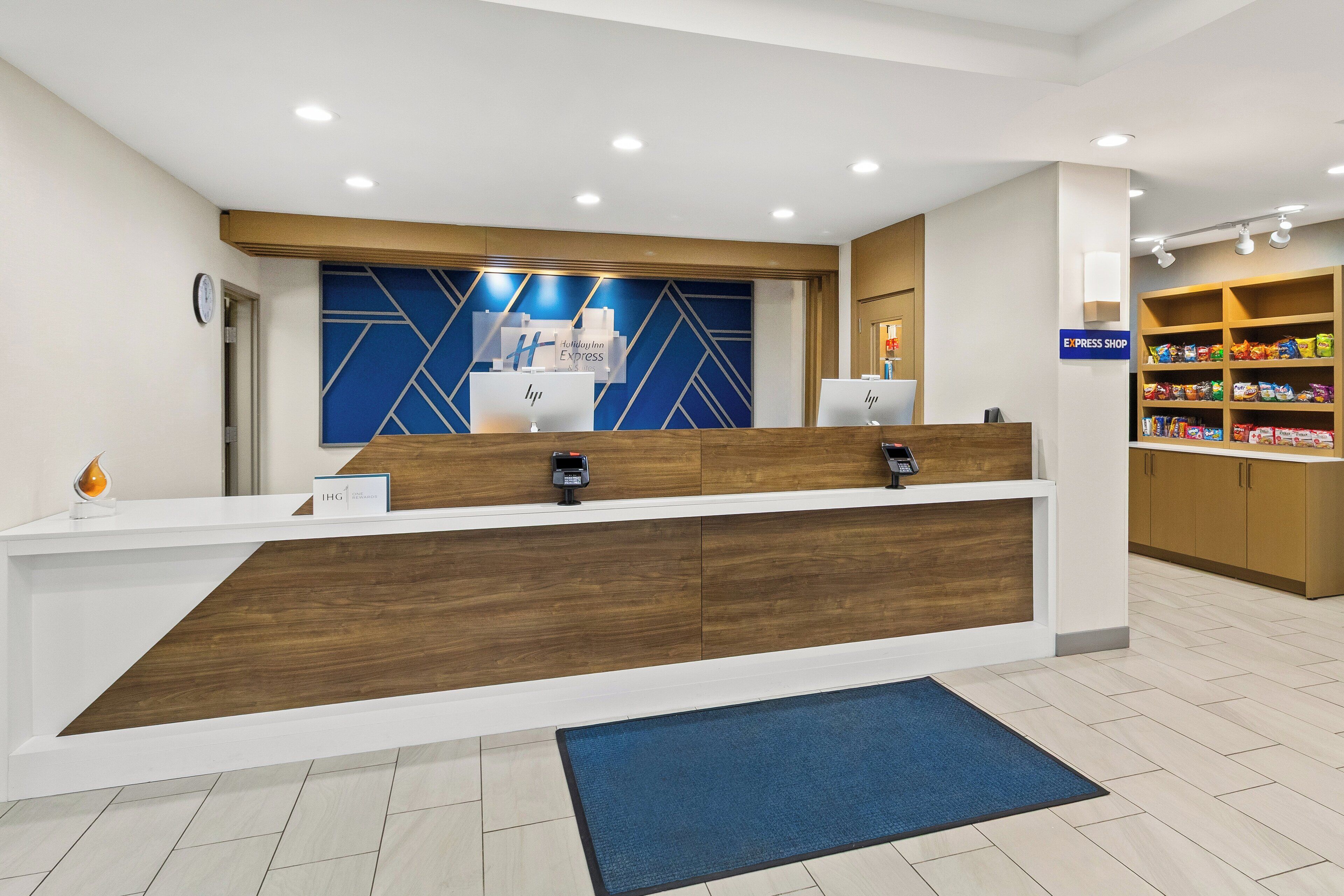 A reception desk with a wooden counter, a blue wall with geometric patterns, and a sign for Holiday Inn Express.