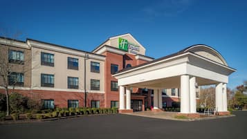 Een Holiday Inn Express hotel met een gevel van baksteen, een overdekte ingang en een helderblauwe lucht.