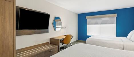 A hotel room with a bed, a desk, a chair, a TV, and a window.
