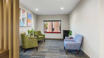 Een moderne lobby met een kamerbreed tapijt, twee fauteuils, een bank en een open haard.