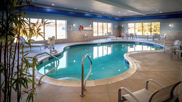An indoor swimming pool with clear water, surrounded by lounge chairs and a tiled floor. - Holiday Inn Express and Suites Fairmont by IHG (Fairmont)