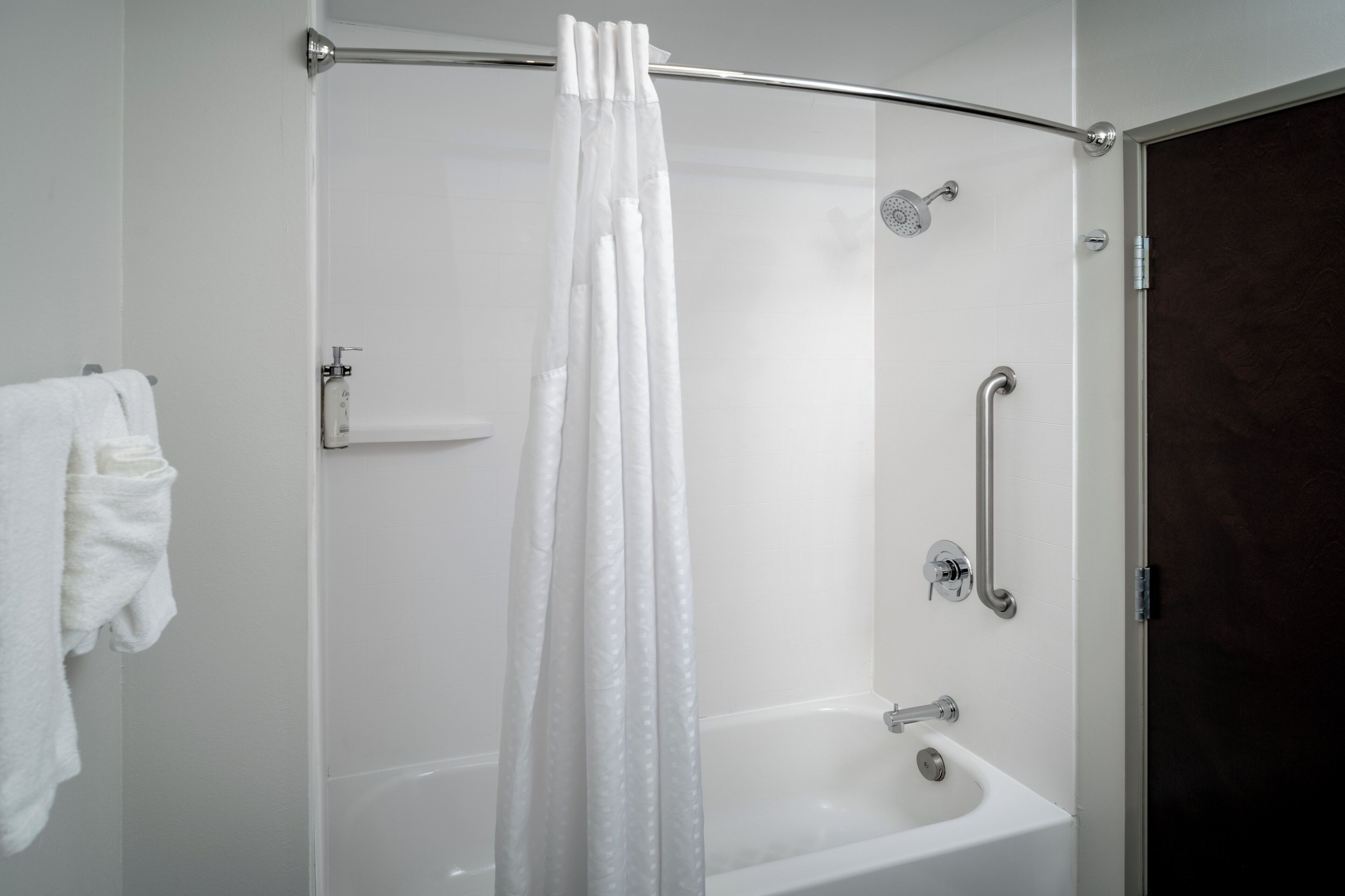 Une salle de bain moderne avec une douche à parois de verre, une baignoire blanche et une barre d’appui.