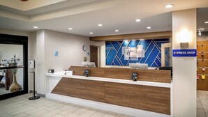 A reception desk with a wooden finish, a clock, and a sign for the Express Shop. - Holiday Inn Express and Suites Fairmont by IHG (Fairmont)